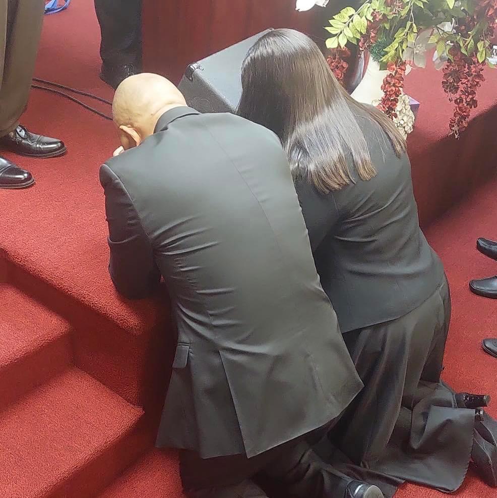 Los pastores Danny y María Reyes arrodillados en oración sobre los escalones del altar durante su consagración